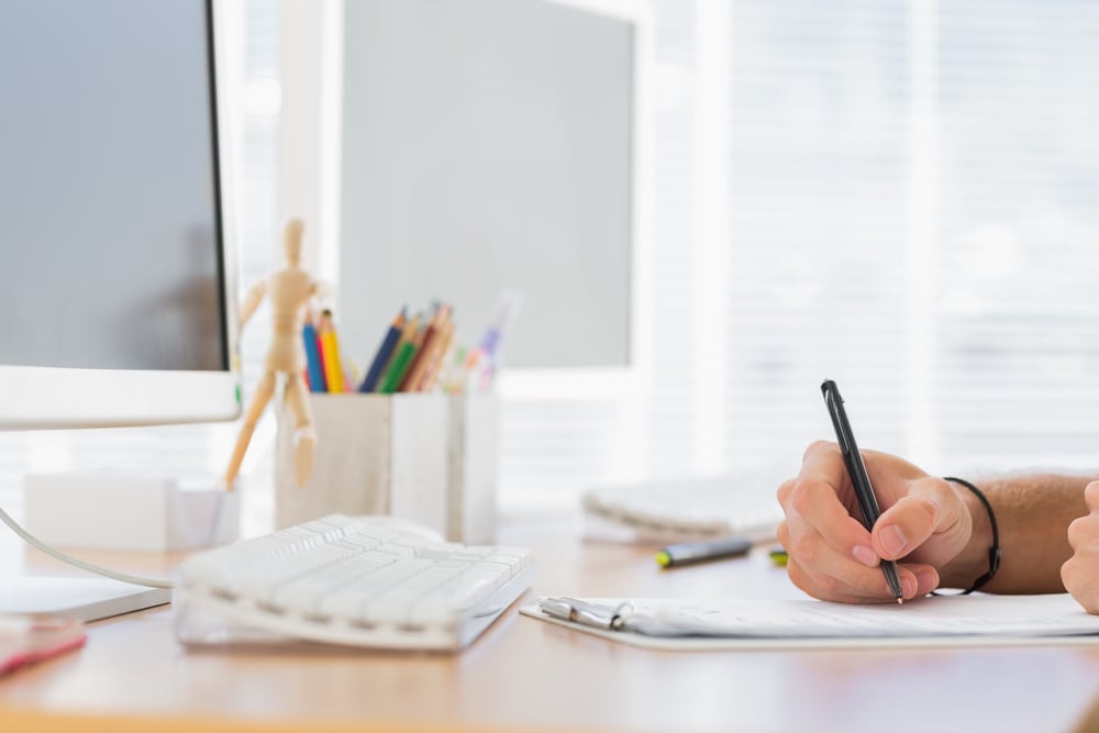 Hand writing in a modern office on a clipboard